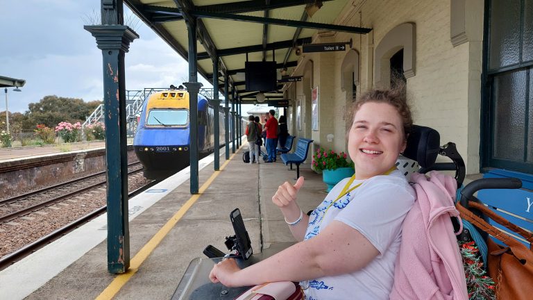 Person in wheelchair posing in front of train